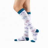 Chaussettes de compression modèle "Coeur ECG" blanches et vertes portées sur jambes de femme